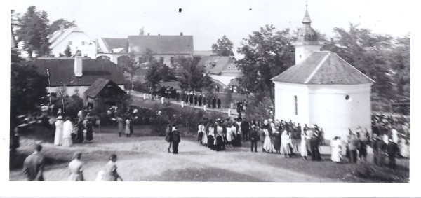 Vysvěcení kaple. Na návsi dřevěná pastouška.